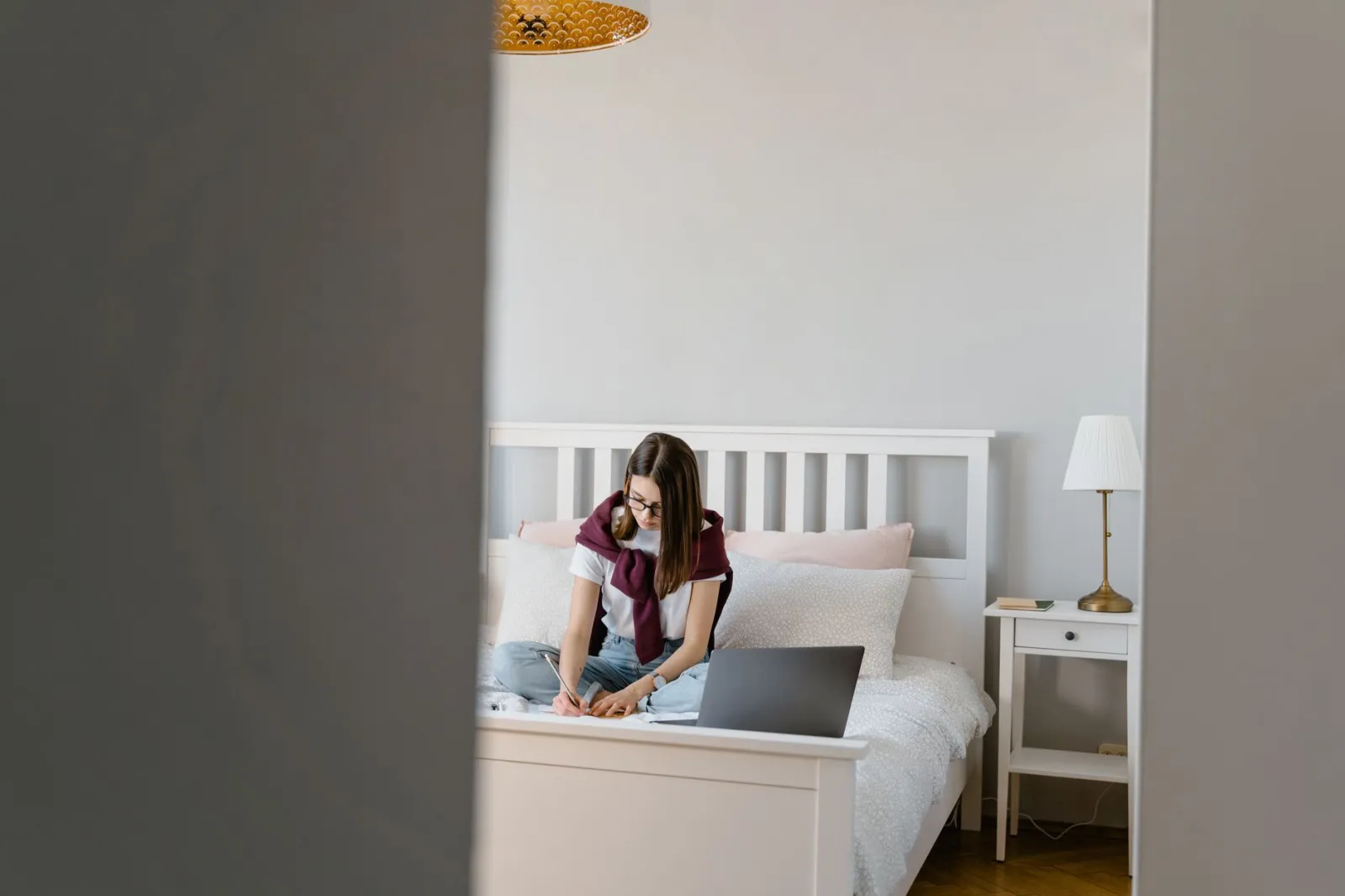 Teen girl focused on homework in a peaceful bedroom setting. Casual, educational scene.